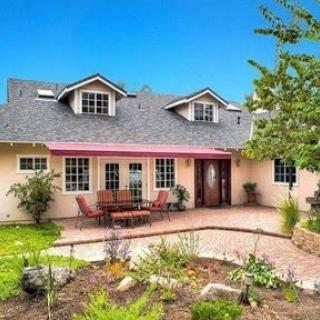 A charming house with beautiful landscaping and inviting outdoor seating, perfect for enjoying the fresh air.