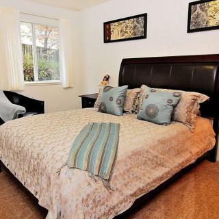 A cozy bedroom with a stylishly made bed, decorative pillows, and wall art.