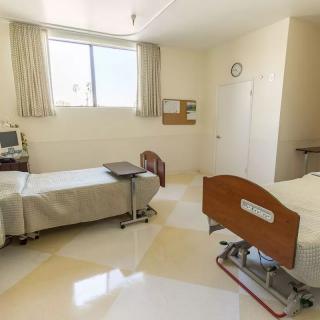 A clean and well-equipped hospital room with two patient beds and medical equipment.