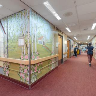 A brightly lit hospital hallway featuring a mural on one wall, creating a calming atmosphere.