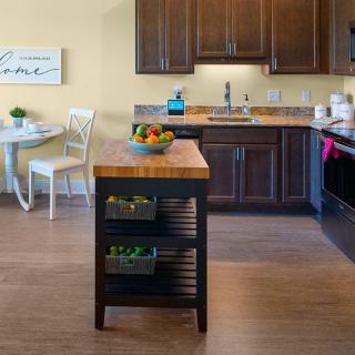 A cozy kitchen with a central island, featuring wooden cabinets and a small dining area.