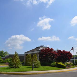 A serene view of a building surrounded by lush greenery under a clear blue sky.
