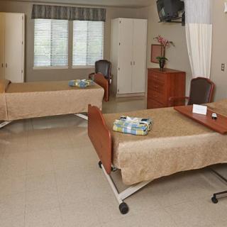 A hospital room with two beds and basic medical furniture.