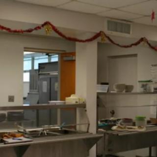 A cafeteria kitchen area with food serving counter and festive decorations.