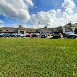 A view of a building with a spacious parking lot under a partly cloudy sky.