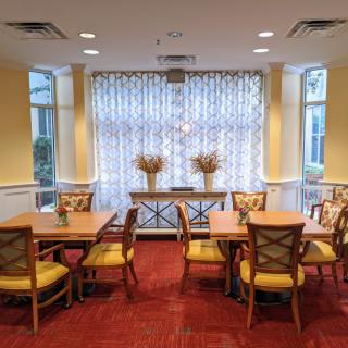 A cozy dining area with tables and chairs, adorned with decorative vases and light curtains.