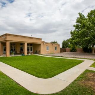 A modern single-story house with a well-maintained lawn and clear pathways under a cloudy sky.