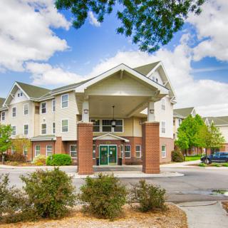 A multi-story residential or hotel building with a landscaped entrance and clear skies.