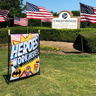 A vibrant sign celebrating local heroes in front of Crestwood, adorned with American flags.