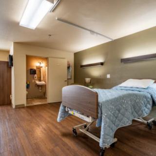 A clean and organized hospital room with a single bed and attached bathroom.