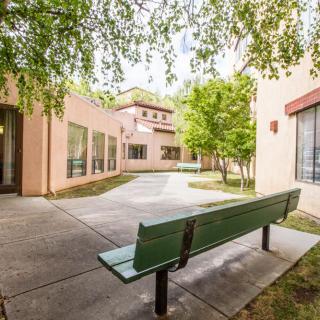 A quiet courtyard with a green bench surrounded by buildings and trees.