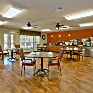 A cozy cafe-style dining area with wooden floors, tables, and chairs.