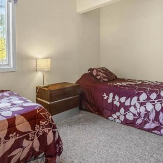 A cozy bedroom with two twin beds adorned with floral bedding, a lamp between them, and a window letting in natural light.