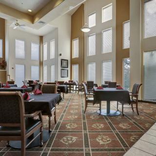 A spacious dining room with high ceilings, large windows, and neatly arranged tables and chairs.