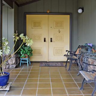 A welcoming porch with a double front door and decorative plants.