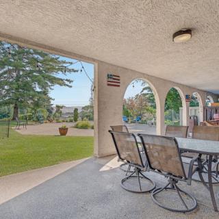 A spacious patio with outdoor furniture overlooking a garden and yard, featuring arched openings for an open view.
