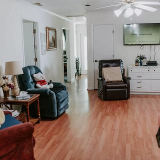 Cozy living room with armchairs, a TV, and wooden flooring.