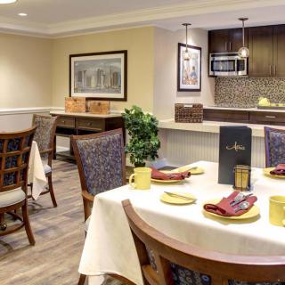 A modern dining area with a well-set table, featuring contemporary decor and kitchen space.