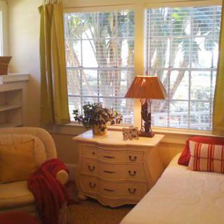 A cozy living room with a sofa, side table, and lamp by large windows.