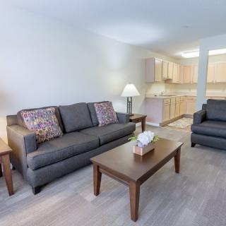 A modern open living room with a comfortable sofa set and a view of the kitchen area.