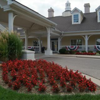 A beautifully landscaped entrance with vibrant red flowers in front of a large building.