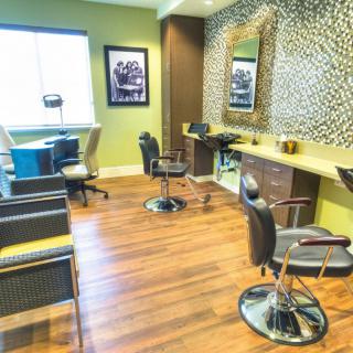A stylish and modern salon with barber chairs and mirrors, featuring a wooden floor and patterned wall design.