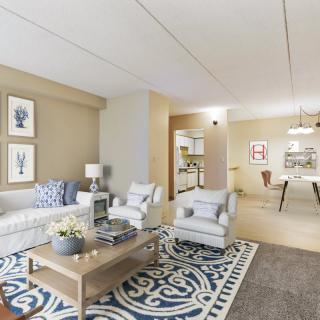 A cozy and elegantly decorated living room featuring a sofa, armchairs, a coffee table, and artwork on the walls.