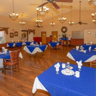 A spacious dining room with blue tablecloths and elegant chandeliers.