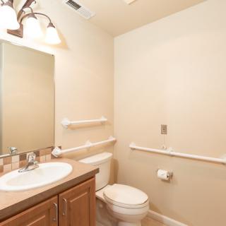 A well-lit bathroom with a sink, mirror, and toilet.