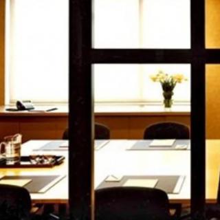A neatly arranged conference room with a large table and chairs, featuring a decorative vase by the window.