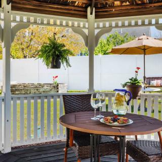 A cozy gazebo featuring a table set for dining with plants and a garden view.