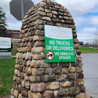 A stone structure displaying a sign that prohibits trucks and deliveries at this entrance.