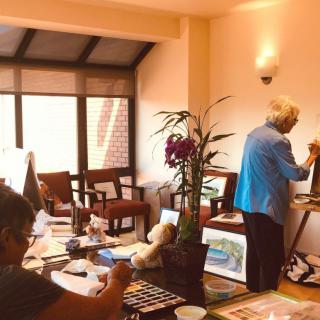 Artists working in a cozy art studio filled with paintings and creative materials.