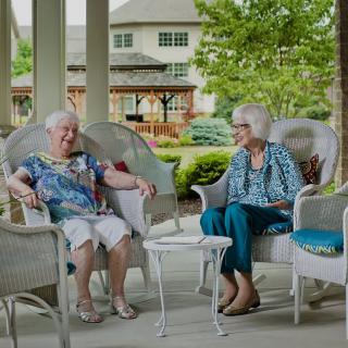 Two elderly women enjoying a conversation on a patio.