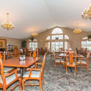 A spacious dining room with wooden tables and chairs, large windows, and elegant lighting fixtures.