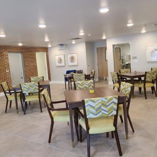 A modern dining area with neatly arranged tables and chairs under bright lighting.