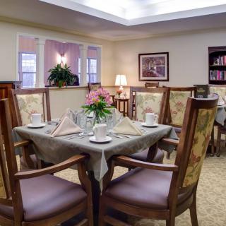A cozy and elegantly decorated dining room with a neatly set table and comfortable chairs.