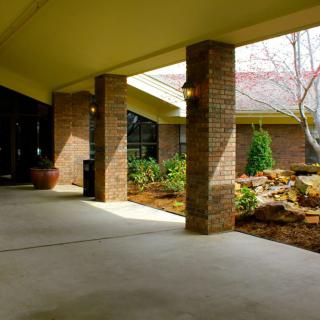 The entrance of a building featuring brick columns and landscaped surroundings.