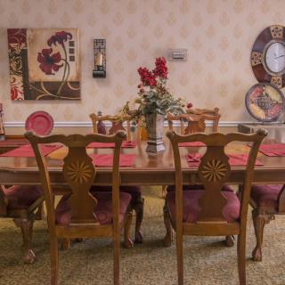 A dining room with a wooden table and chairs, adorned with floral decorations and wall art.