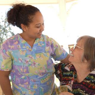 A caregiver shares a warm moment with an elderly person.