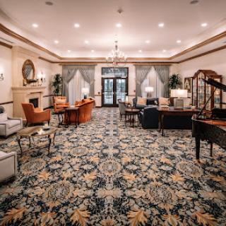 A beautifully designed lobby featuring elegant furniture and a patterned carpet, illuminated by warm lighting.