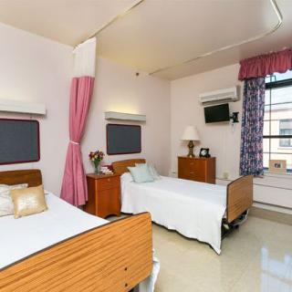 A clean and comfortable hospital room with two beds, curtains, and windows.