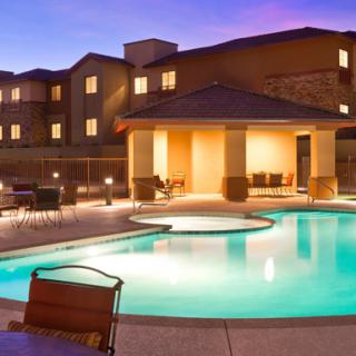 A well-lit outdoor pool area at a resort during the evening.