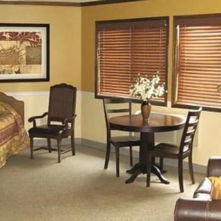 A cozy bedroom interior with a small dining area, featuring a table and chairs near the window.