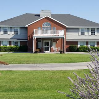 A large residential house with a well-maintained lawn and clear blue sky.