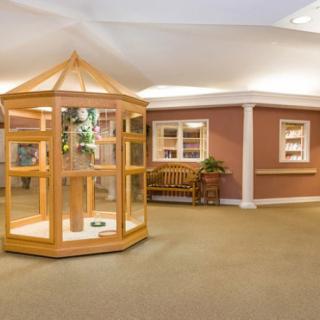 A spacious lobby area featuring a central wooden display, a bench, and decorative plants.