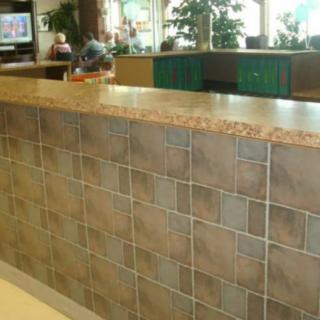 A tiled counter in a public indoor setting with furniture and plants in the background.