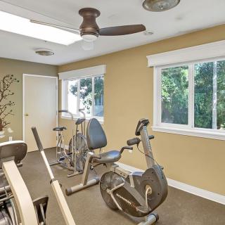 A well-lit home gym with stationary bikes and a treadmill.