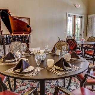 A beautifully set dining table in an elegant room with a grand piano in the background.