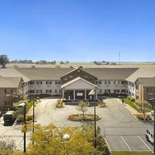 A residential building with a parking lot and landscaped surroundings under a clear blue sky.